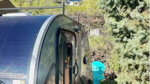 Une cellule de camping équipée d’un panneau solaire, d’une porte et d’une bâche bleue.