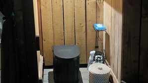 Un petit espace extérieur clos, délimité par une clôture en bois, avec un radiateur noir, une petite table et un parasol bleu.
