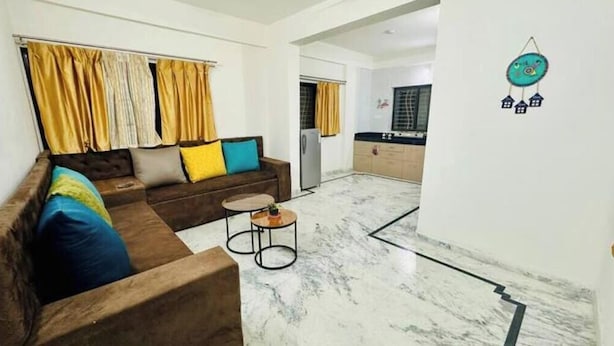 A living room with a sofa, a small round table, and a kitchen in the background.