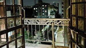 An open balcony with metal railings and a view of a cityscape at night.