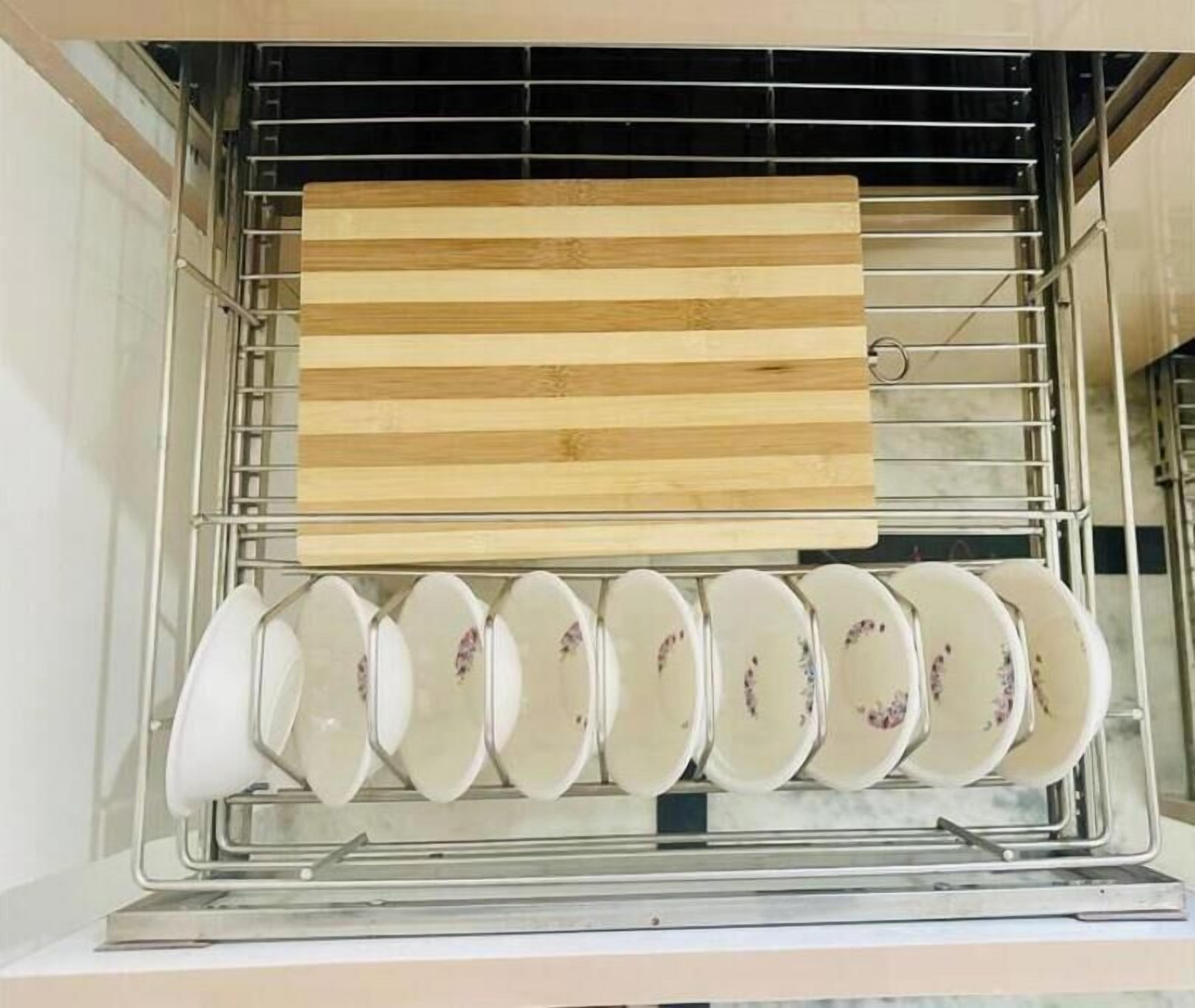 A kitchen with a drying rack holding wooden cutting boards and a row of white plates with floral designs.