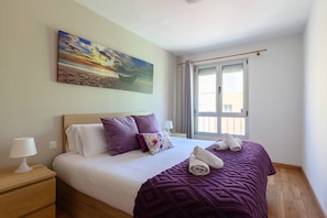 Hotelkamer met een bed, nachtkastje, lamp, schilderij, raam en uitzicht.