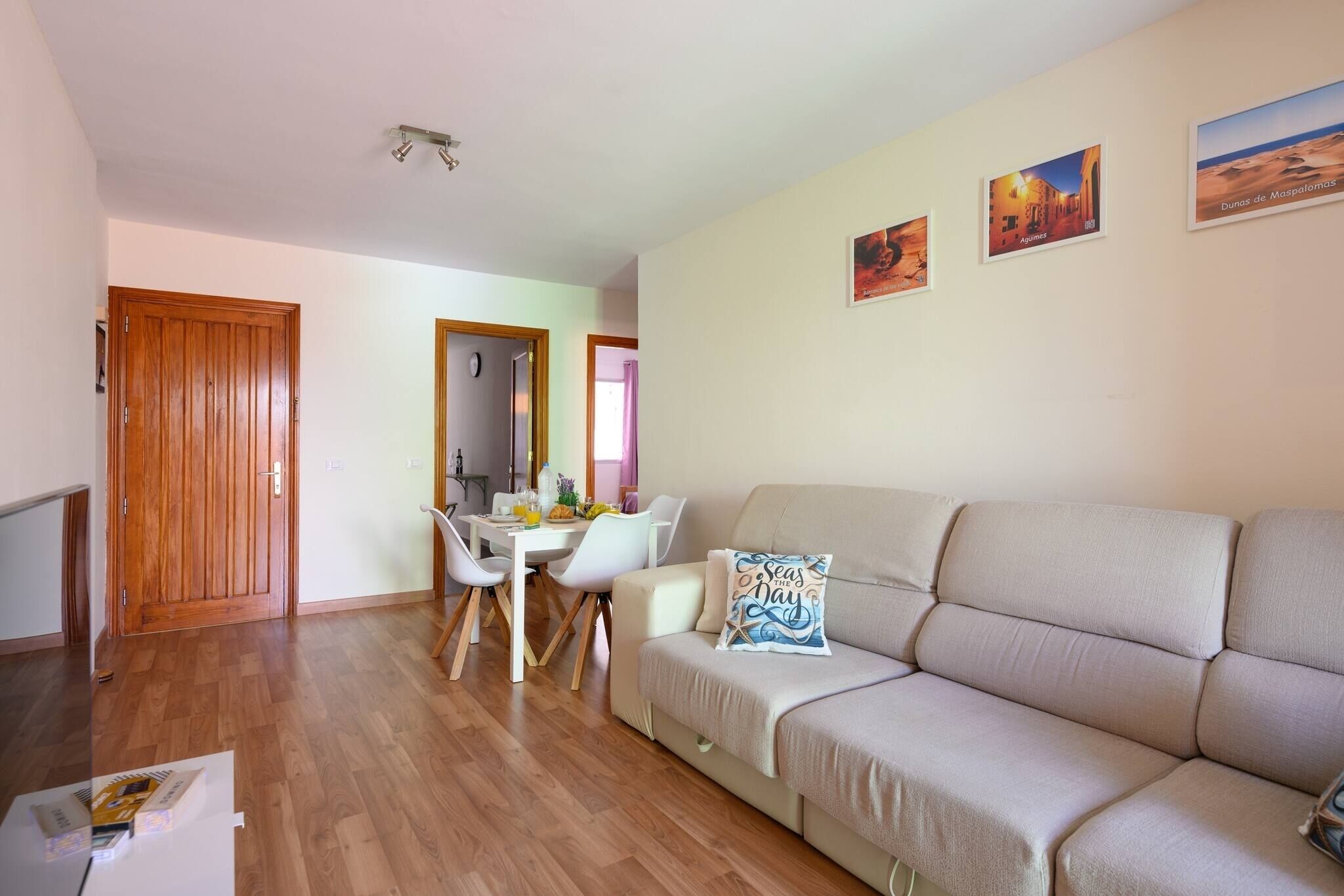 Een woonkamer met een bank, een eettafel met stoelen en een houten deur.
