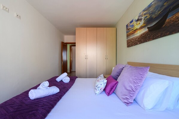 A hotel room with a bed, a wardrobe, and a painting on the wall.
