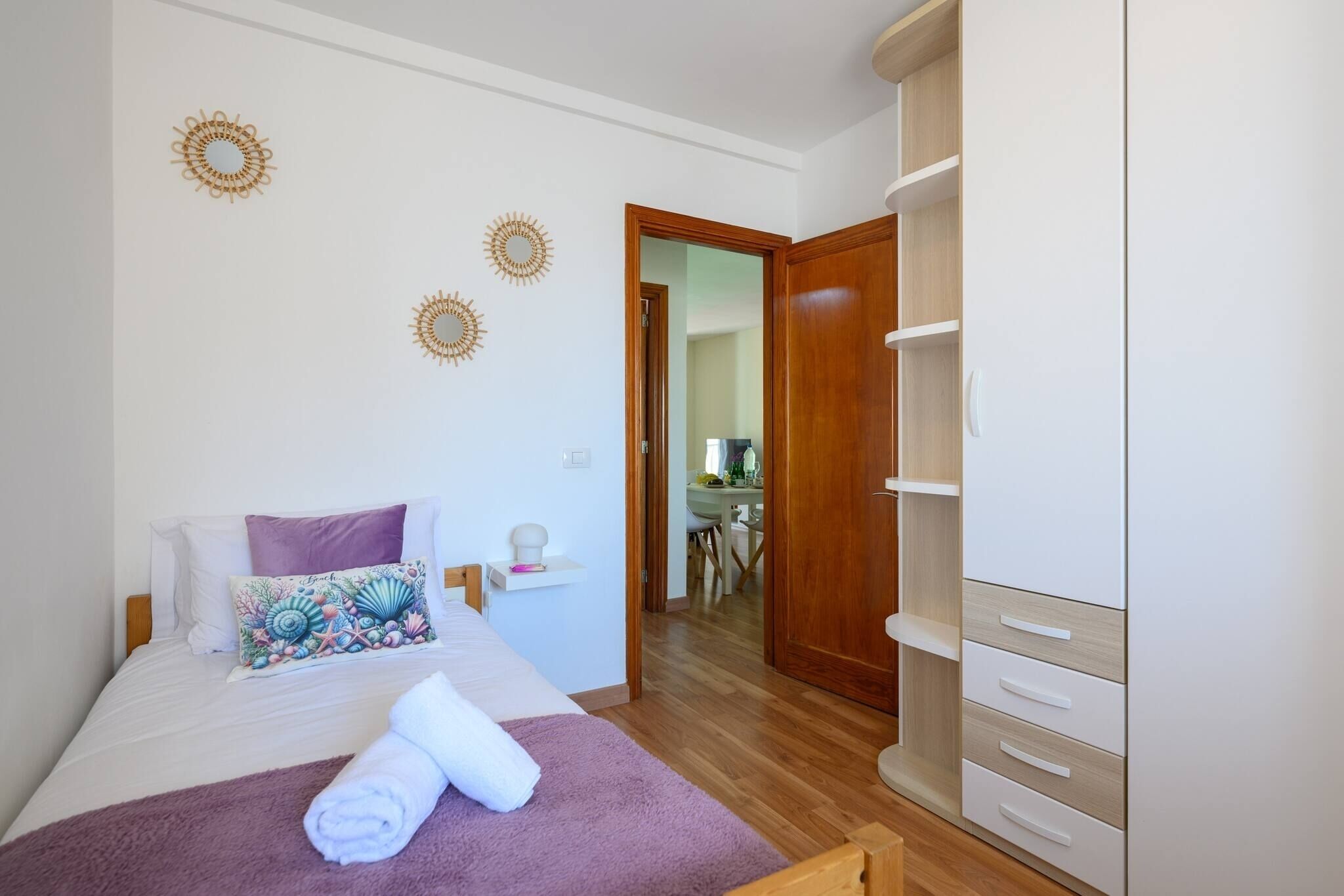 Un dormitorio con cama, armario de madera y puerta que da a un comedor.