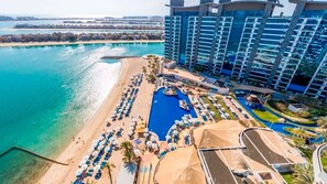 Een resort met een groot zwembad, een strandgedeelte en een hoog gebouw.
