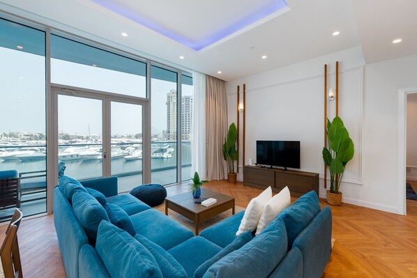 A modern living room with a large sofa, a coffee table, and a TV.