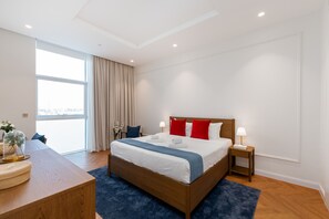 A modern hotel room with a large bed, a desk, and a view of the city.