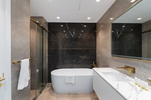 Een moderne badkamer met een vrijstaand bad, een douchecabine van glas en een wastafel met een grote spiegel.