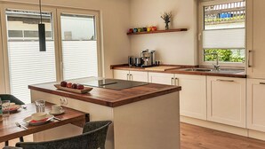A modern kitchen with a central island, wooden countertops, and a dining area with a table and chairs.