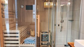 A sauna room with wooden benches, a glass partition, and a glass-enclosed shower area.