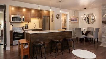 A modern kitchen with wooden cabinets, stainless steel appliances, and a bar area with stools.