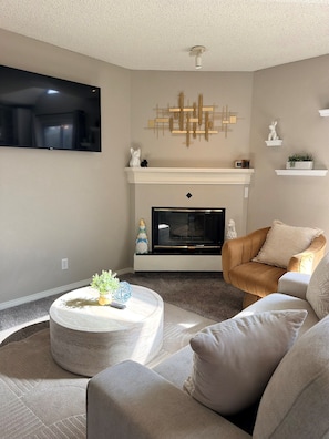 A living room with a fireplace, a mounted TV, and a brown leather armchair.