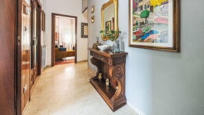 Um corredor com piso de madeira, um espelho, um quadro emoldurado e uma porta que dá para outro quarto.