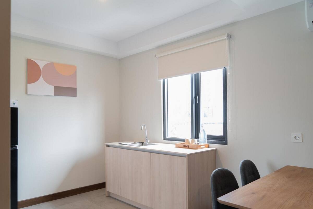 A compact kitchen with a window, a sink, and a dining area with chairs.