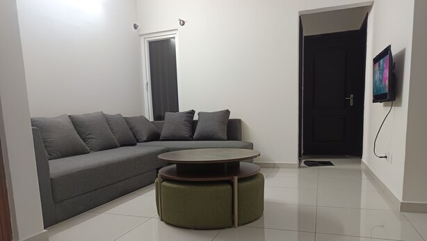 A living room with a grey sofa, a round coffee table, and a green ottoman.