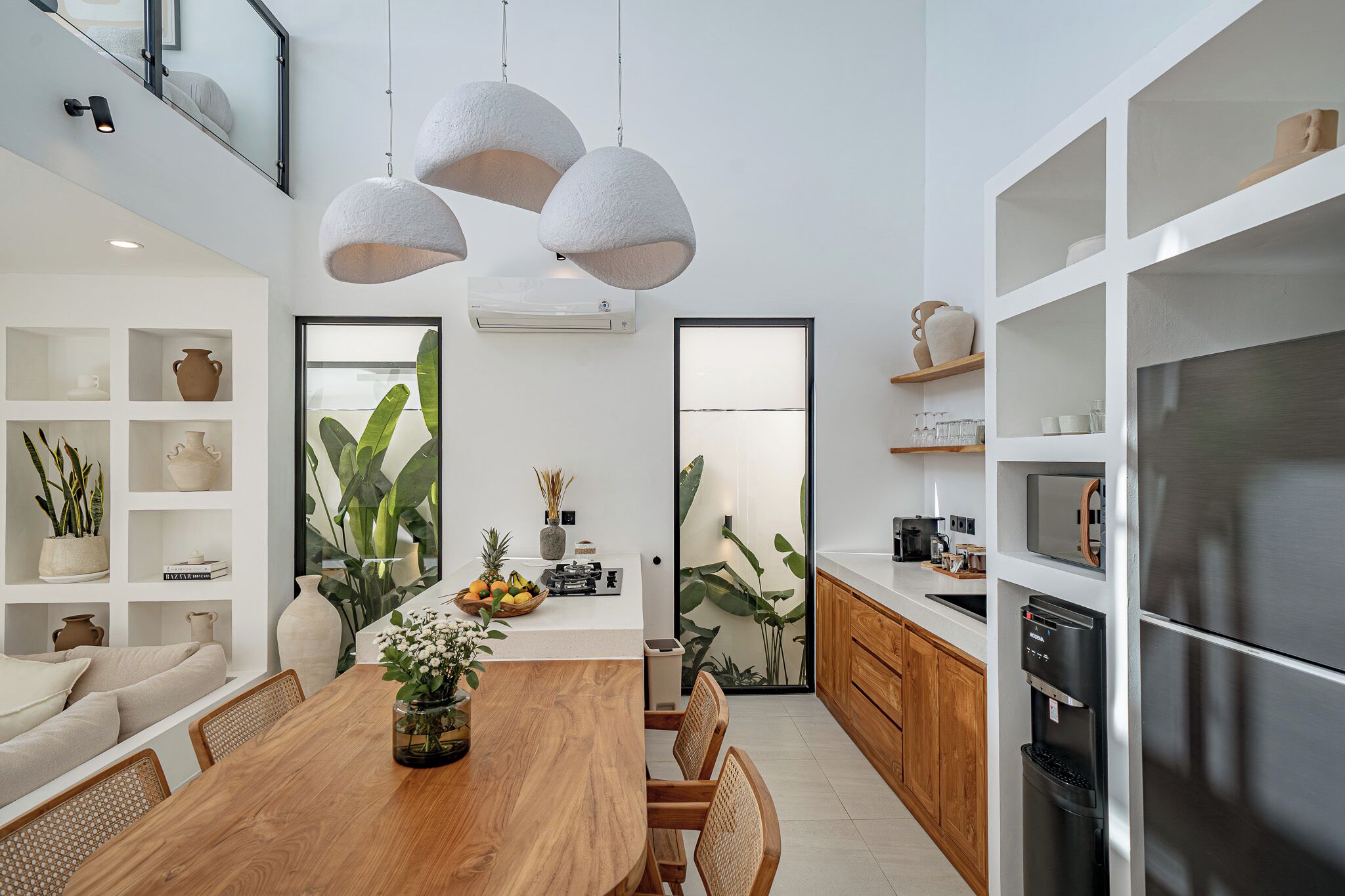 A modern kitchen with a wooden dining table, white cabinets, and a built-in refrigerator.