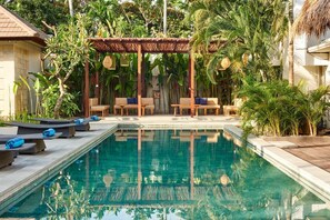 A pool area with lounge chairs and a pergola. - KU Villas (Kuta)