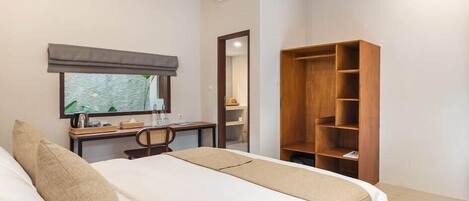 A hotel room with a bed, a desk, a chair, a wardrobe, and an air conditioning unit.