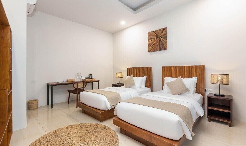 Habitación de hotel con dos camas, un escritorio y una mesita.