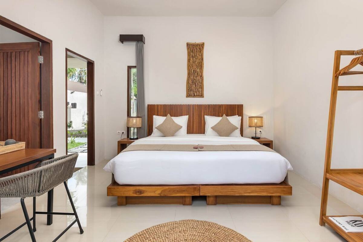 A bedroom with a wooden bed, bedside tables, a desk, and a chair.