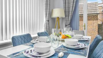 A dining area with a table set for four, including bowls, glasses, and cutlery.