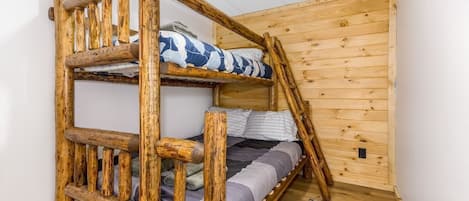 Una cama litera con estructura de madera y una alfombra de cuadros en el suelo.