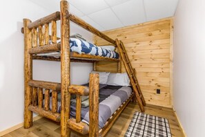 Een stapelbed met houten frame en een geruit vloerkleed.