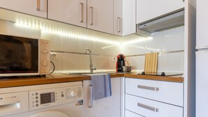 Una cucina compatta con microonde, macchina per il caffè e lavatrice.