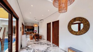 A hallway with a marble floor, wooden doors, and a large mirror on the wall. - Budayana Villa (Jimbaran)