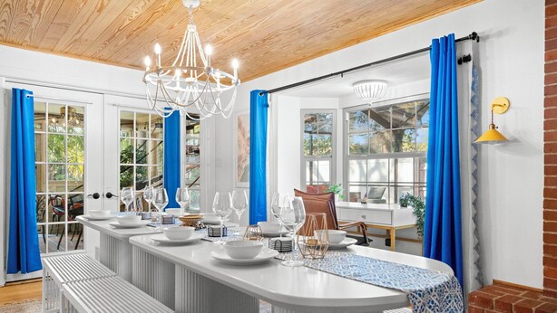 A modern kitchen with a central island, white cabinetry, and blue curtains.