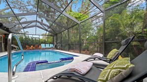 A glass-enclosed pool area with lounge chairs and a pool ladder.
