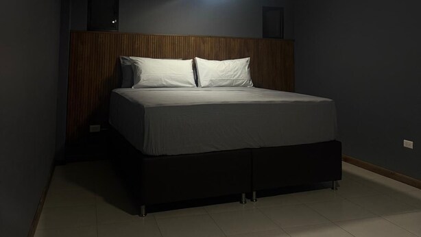 A bedroom with a bed, a wooden headboard, and a ceiling light.