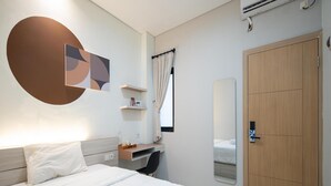 Una habitación de hotel moderna con cama, escritorio, silla, armario y equipo de aire acondicionado.