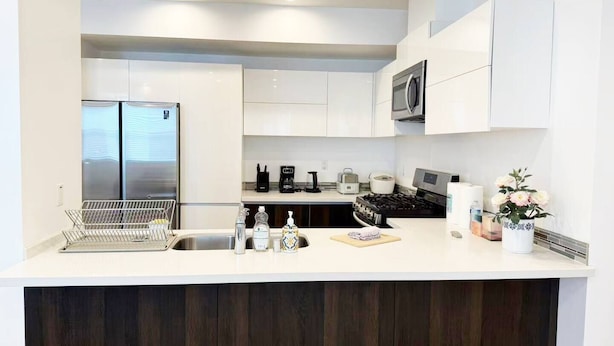 A modern kitchen with white cabinets, stainless steel appliances, a built-in oven, and a microwave.