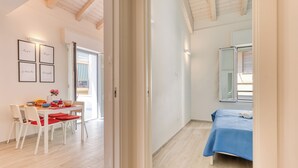 Un dormitorio moderno con una cama, un ventanal y una puerta que da a un comedor.