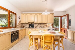 A kitchen with wooden cabinets, a dining table with chairs, a stove, and a sink.