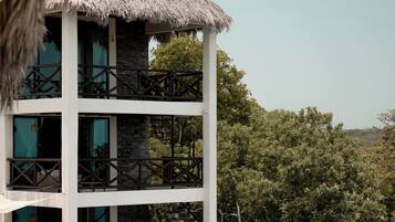 A multi-story building with a pool, stone steps, and a thatched roof.