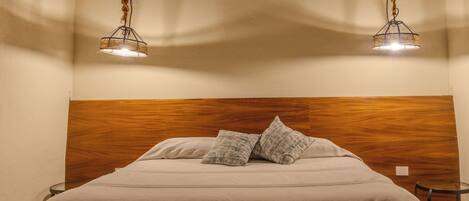 Un dormitorio con cabecera de madera, una cama con almohadas y un banco con toallas enrolladas.