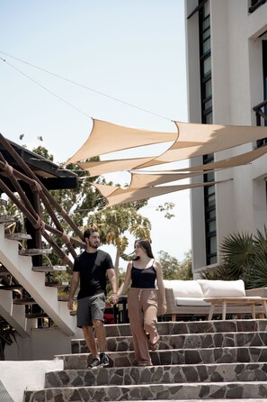 Un hombre y una mujer suben escalones de piedra hacia un edificio blanco de diseño moderno.