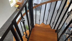 Eine Holztreppe mit schwarzen Metallgeländern führt zu einem Essbereich mit Tisch und Stühlen.