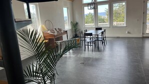 Ein geräumiger Raum mit großem Fenster, einer Holzbank, einem Esstisch mit Stühlen und einem Blumentopf.