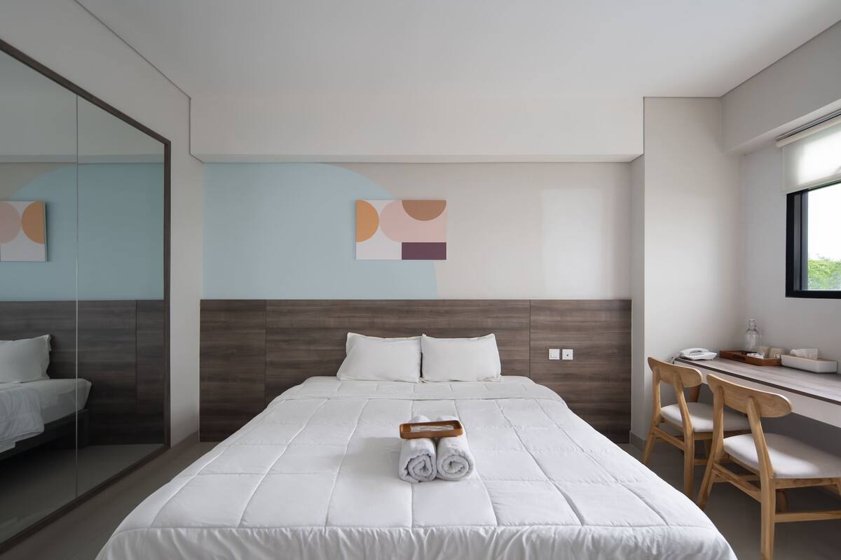Ein modernes Hotelzimmer mit einem großen Bett, einem Schreibtisch mit Stühlen und einem Fenster.