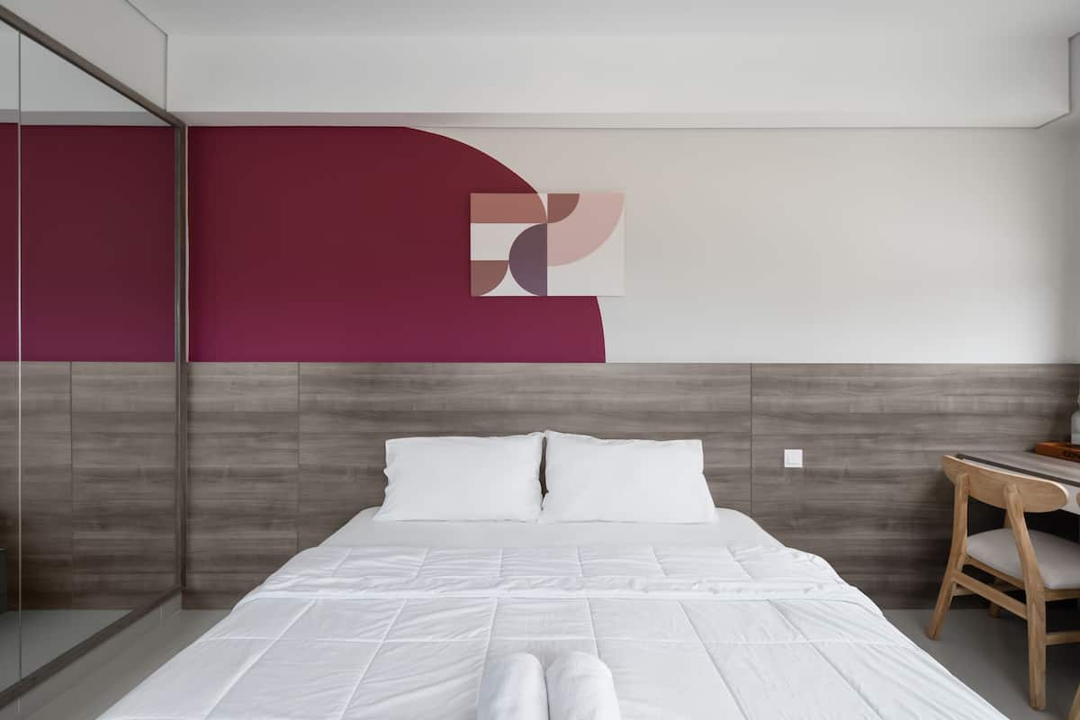 Ein modernes Hotelzimmer mit einem großen Bett, einem Holztisch und einem großen Spiegel.