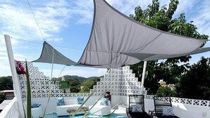 Zona de piscina con valla blanca, sillas de descanso y un toldo grande.
