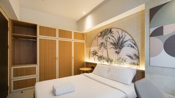 A hotel room with a bed, a wardrobe, a round wall decoration, and a small table.