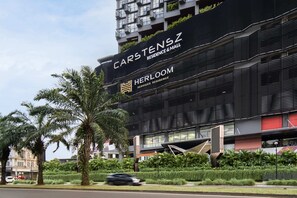 Un bâtiment moderne avec une enseigne indiquant « Carstenz Residence & Mall » et « Herloom Serviced Residence ».