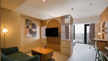 A modern living room with a flat-screen TV, a wooden coffee table, and a green sofa.