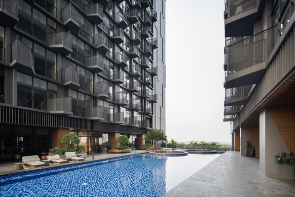 Un bâtiment moderne doté d’une piscine sur le toit, de nombreux balcons et d’espaces de détente en plein air.