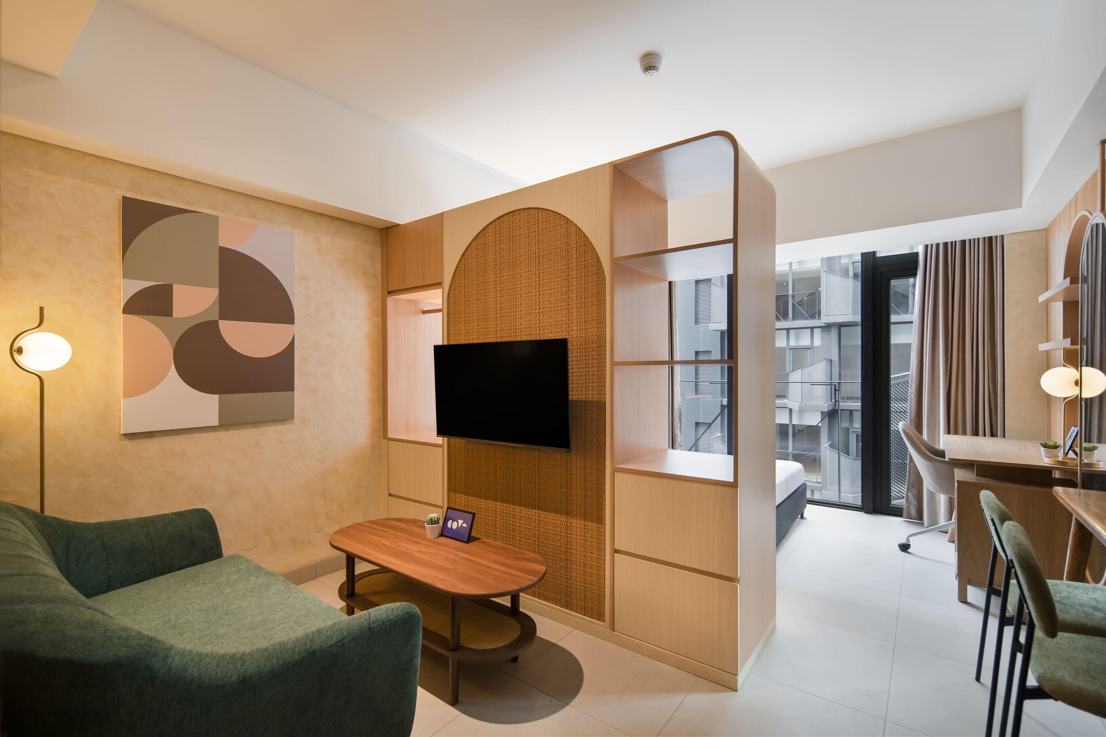 Una habitación de hotel moderna con sofá, una mesita, televisión y zona de escritorio.